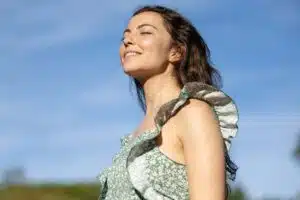 Smiling woman enjoying fresh air outside, representing improved breathing benefits after septoplasty for deviated septum correction.