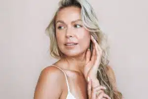 Blonde woman with radiant skin looking aside, highlighting the rejuvenating effects of hyaluronic acid fillers.